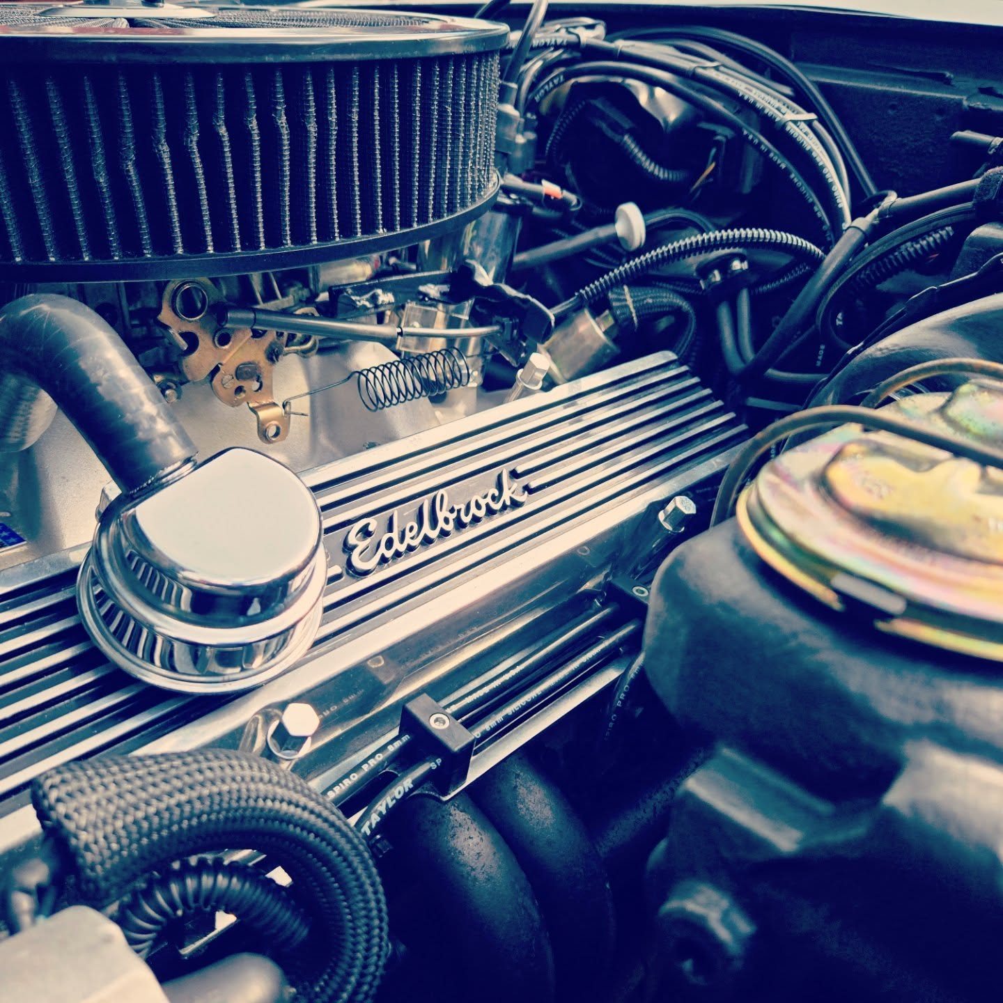 Närbild på en amerikansk V8 med kromad Edelbrock-ventilkåpa, från verkstadsgolvet.